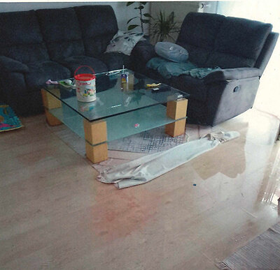 Wohnzimmerboden stark durchgenässt, die Wasserschicht spiegelt die Möbel.